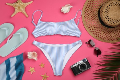 Flat lay composition with swimsuit and beach accessories on pink background