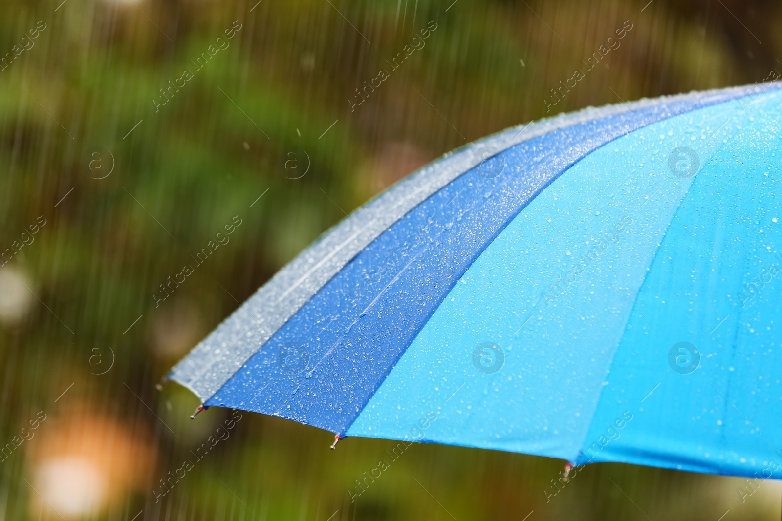 Photo of Bright umbrella under rain on street, closeup