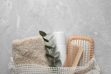 Photo of Dry shampoo spray, towel and hairbrushes with eucalyptus branch on light grey table, top view. Space for text