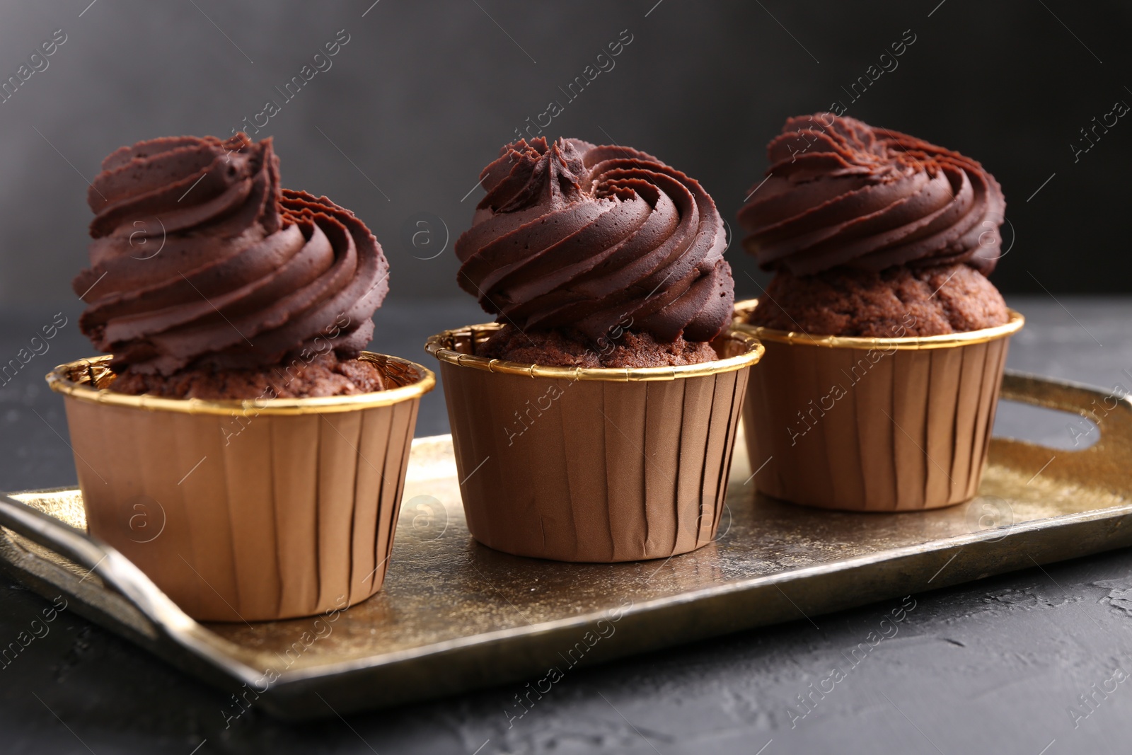 Photo of Delicious chocolate cupcakes on black textured table