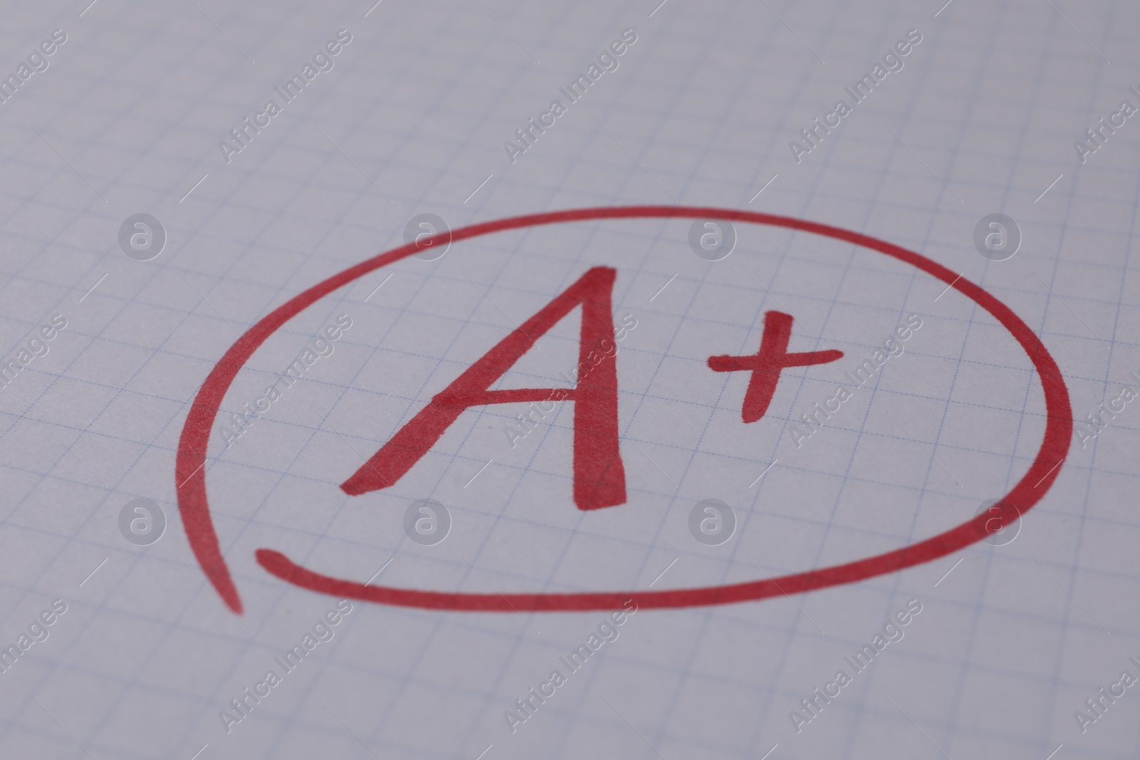 Photo of School grade. Red letter A with plus symbol on notebook paper, closeup