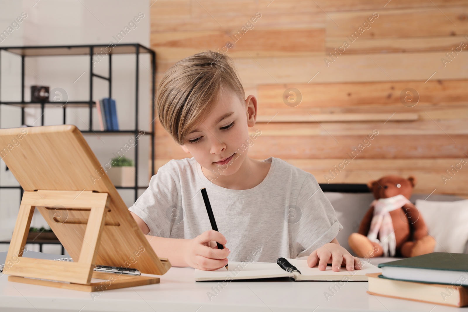 Photo of Cute boy doing homework at table indoors