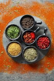 Photo of Different spices and silhouettes of plate on grey table, flat lay