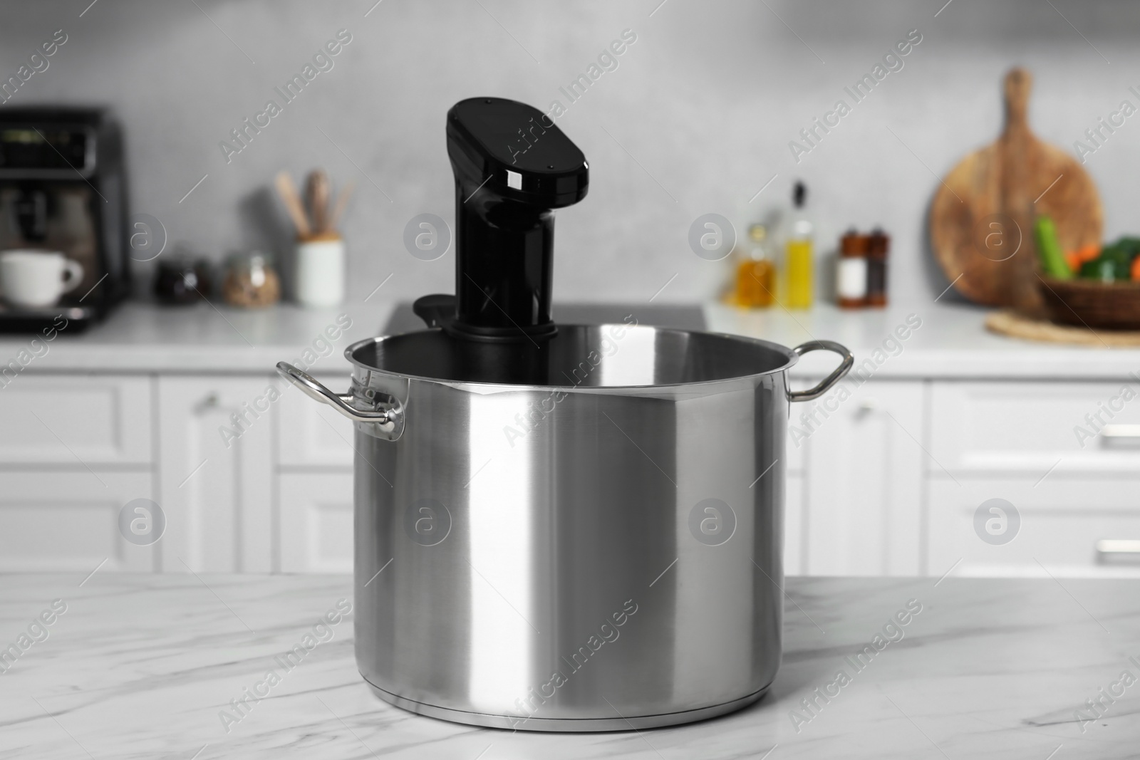 Photo of Pot with sous vide cooker on table in kitchen. Thermal immersion circulator