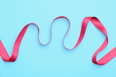 Simple pink ribbon on color background, top view