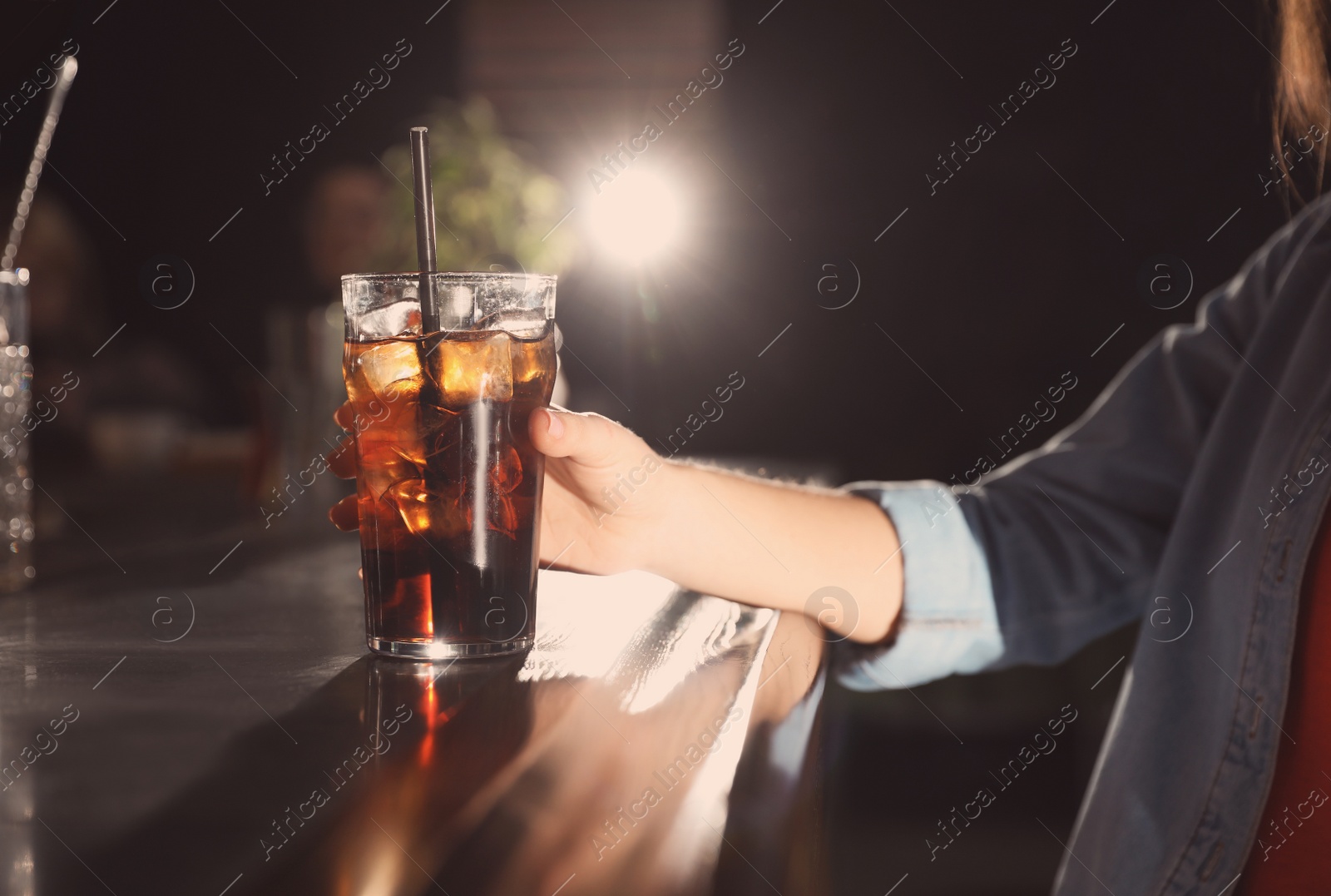 Photo of Woman with glass of refreshing cola at bar counter, closeup