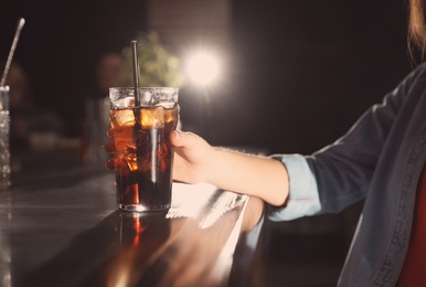 Woman with glass of refreshing cola at bar counter, closeup