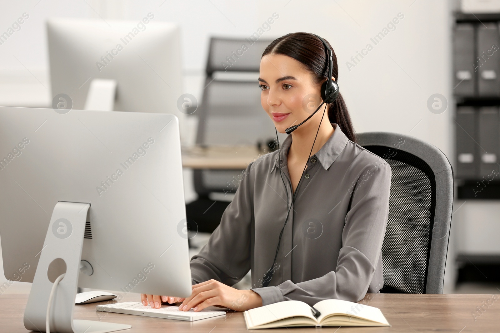 Photo of Hotline operator with headset working on computer in office