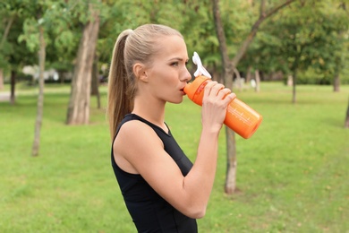 Woman in sportswear drinking protein shake outdoors