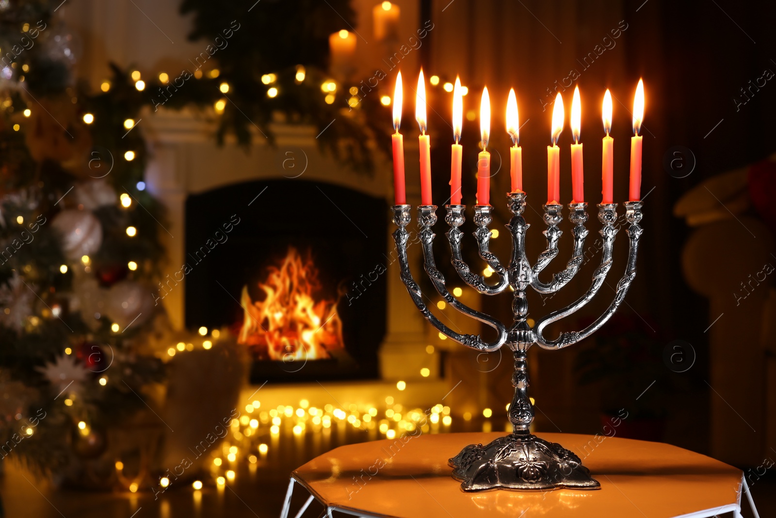 Photo of Silver menorah in dark room with fireplace and Christmas decorations, space for text