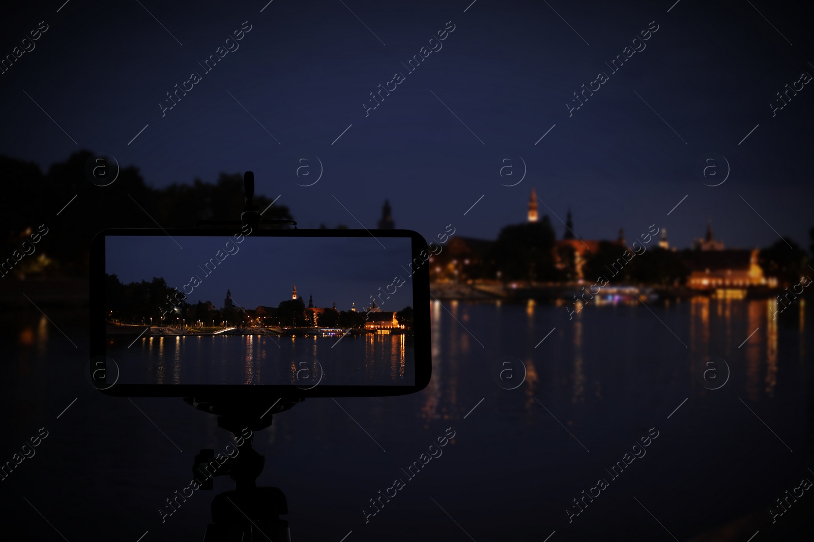 Image of Taking photo of beautiful cityscape at night with smartphone mounted on tripod