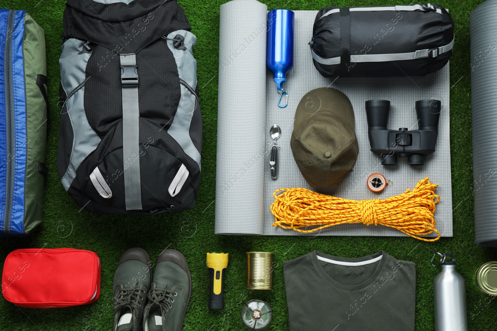Photo of Flat lay composition with different camping equipment on green grass