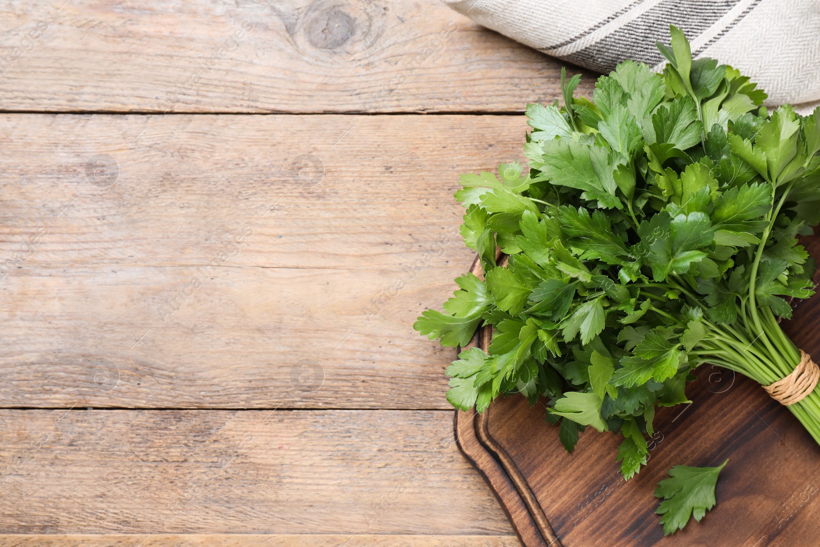 Photo of Bunch of fresh green parsley on wooden table, top view. Space for text