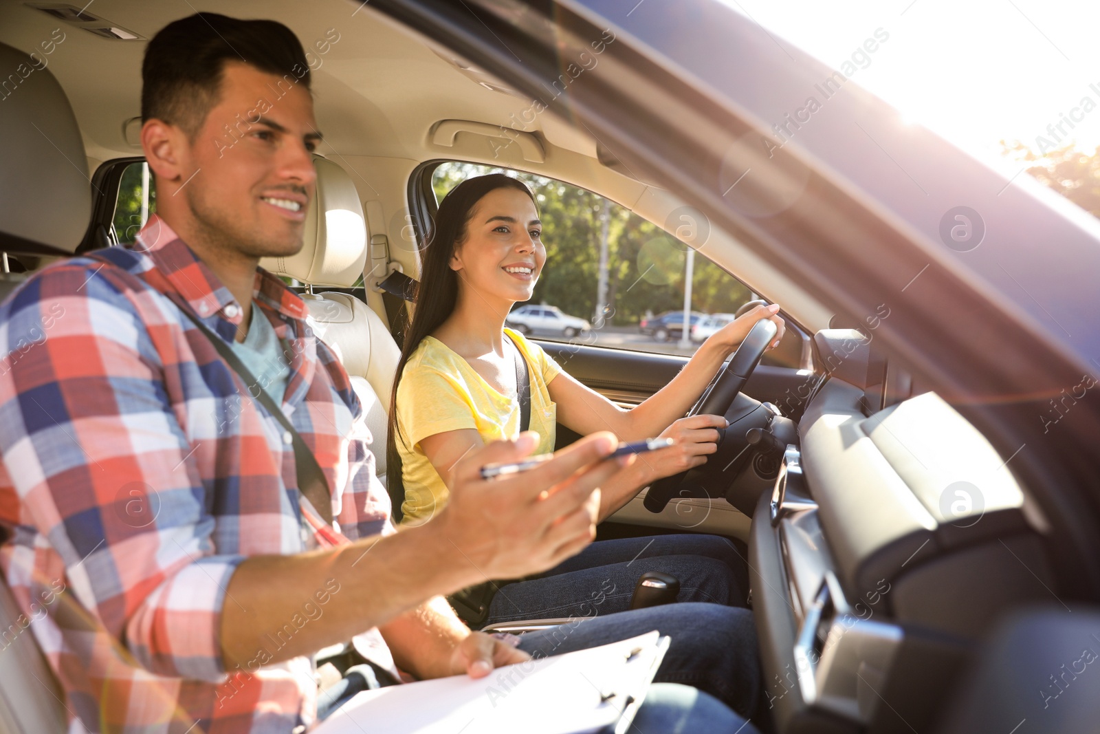 Photo of Young woman in car with instructor. Driving school