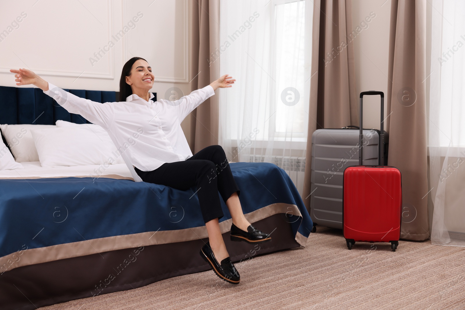 Photo of Beautiful young business woman relaxing on bed in hotel room