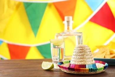 Photo of Mexican sombrero hat and tequila on wooden table. Space for text