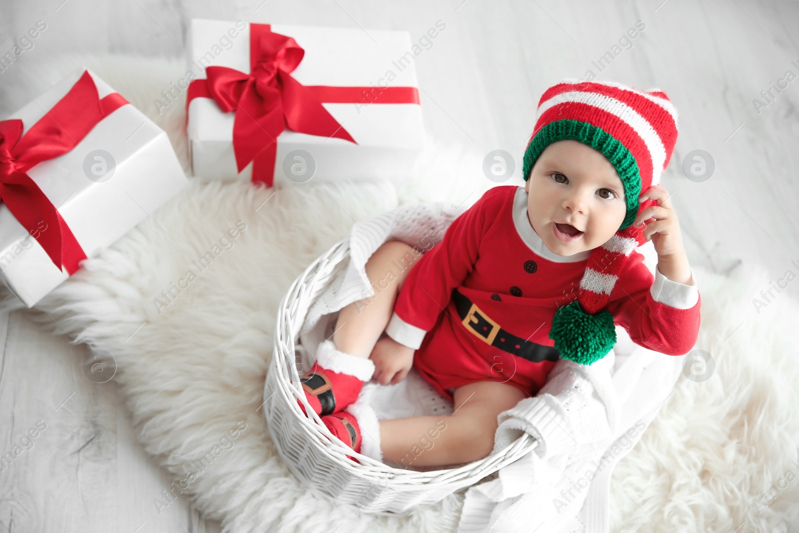 Photo of Cute little baby wearing Christmas costume in basket at home