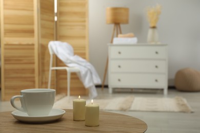 Wooden table with candles and cup, space for text. Interior design
