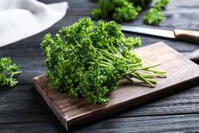 Photo of Fresh curly parsley and cutting board on black wooden table