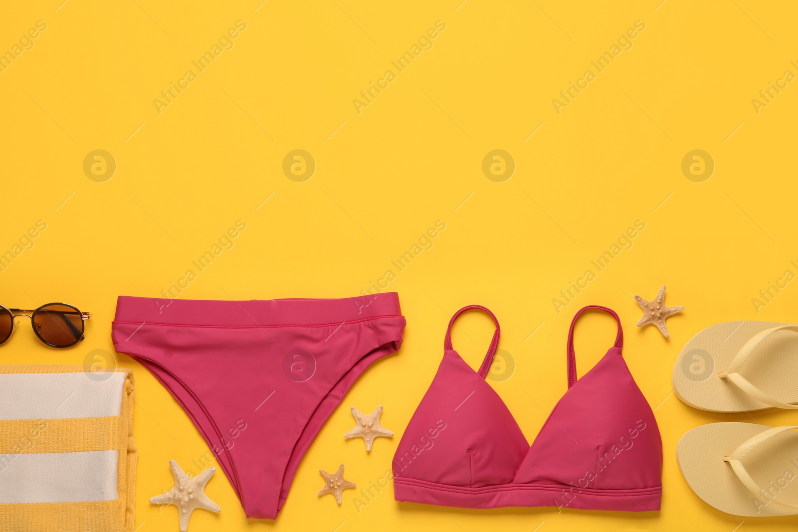 Photo of Stylish bikini and beach accessories on yellow background, flat lay. Space for text