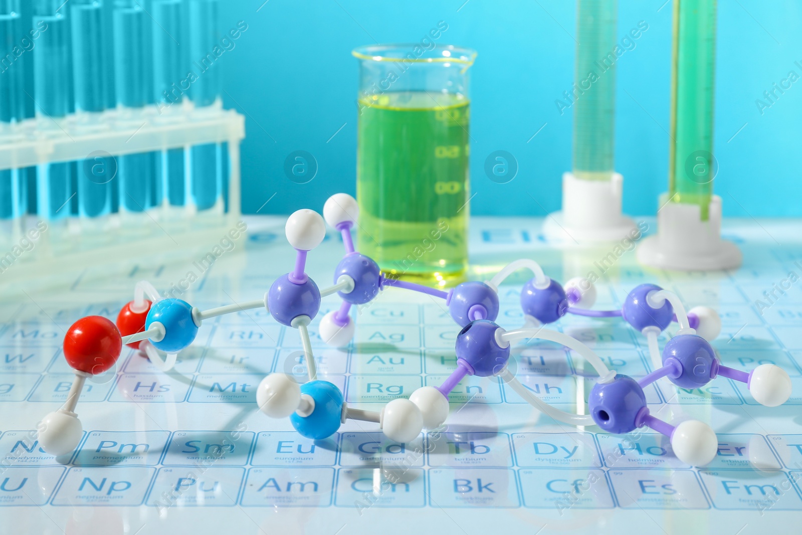 Photo of Molecular model and laboratory glassware on periodic table against light blue background