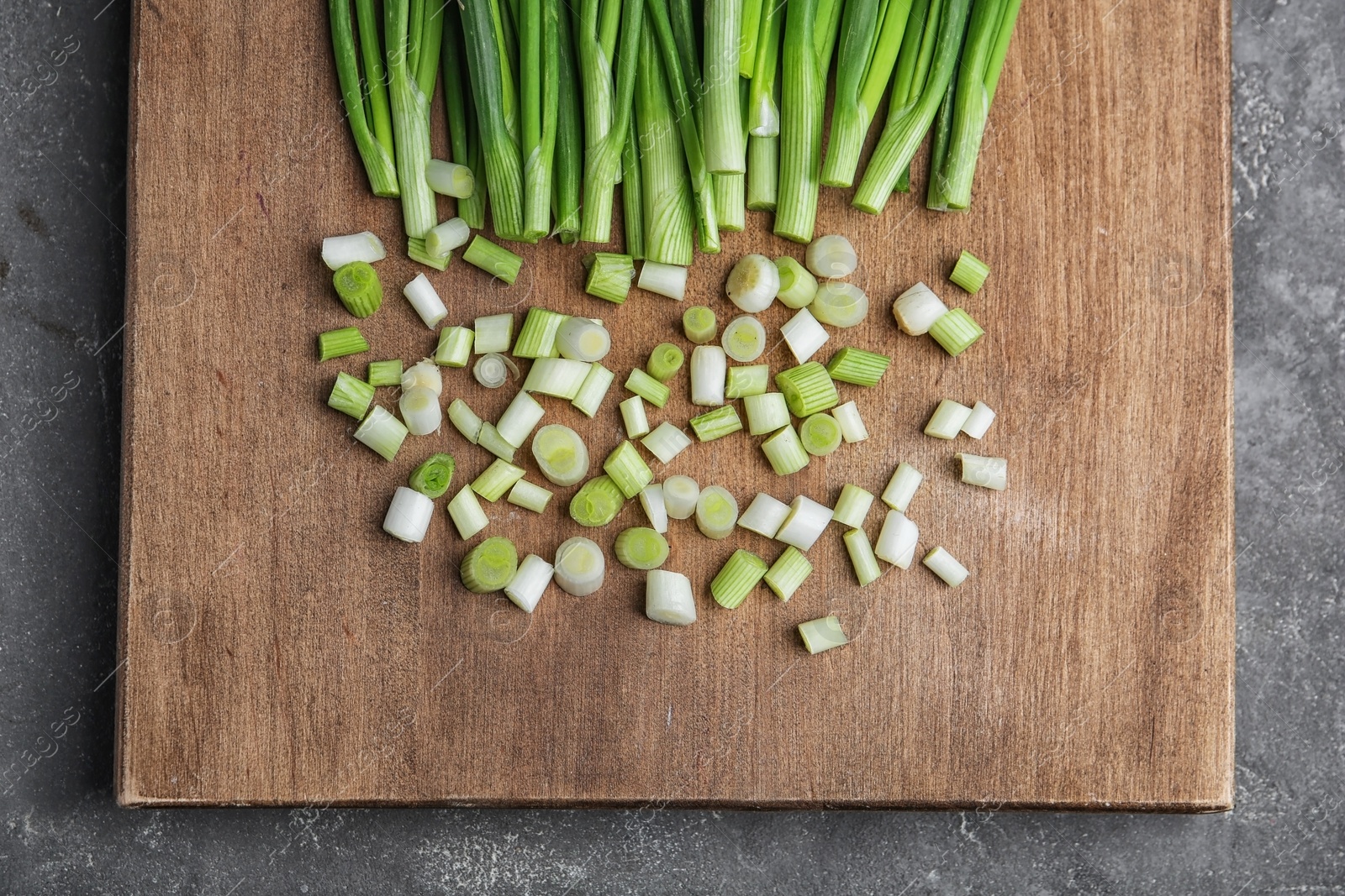 Photo of Fresh green onion on wooden board, top view