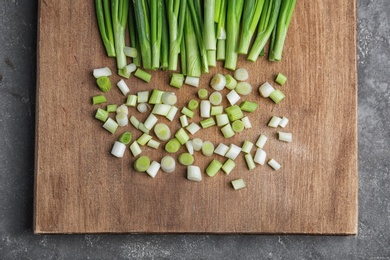 Photo of Fresh green onion on wooden board, top view