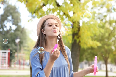 Photo of Young woman blowing soap bubbles in park