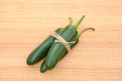 Photo of Fresh ripe green jalapeno peppers on wooden table, top view