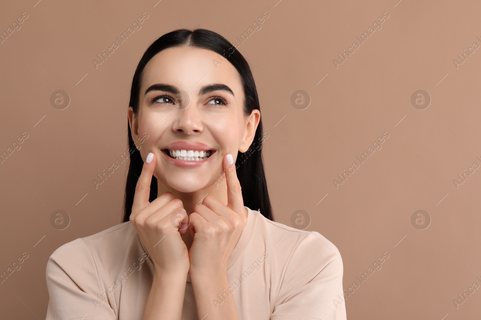 Photo of Beautiful woman showing her clean teeth and smiling on beige background, space for text