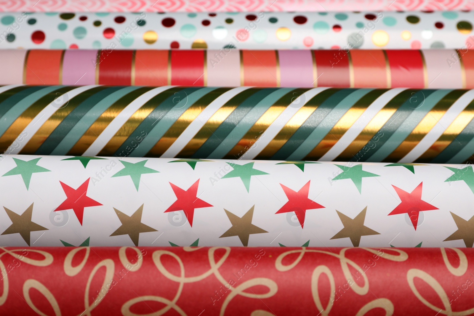 Photo of Different colorful wrapping paper rolls as background, closeup