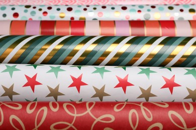 Photo of Different colorful wrapping paper rolls as background, closeup