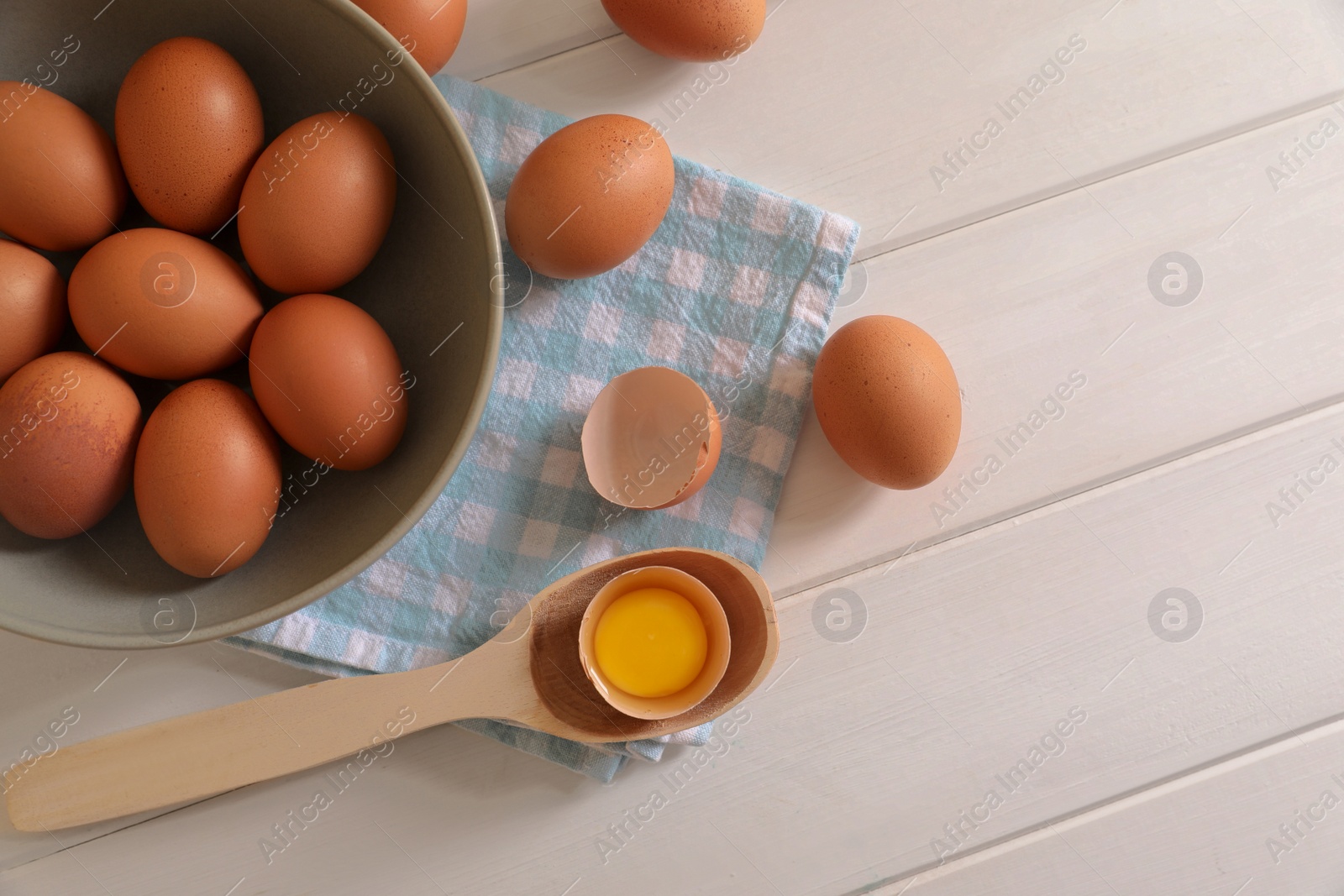 Photo of Cracked and whole chicken eggs on white wooden table, flat lay