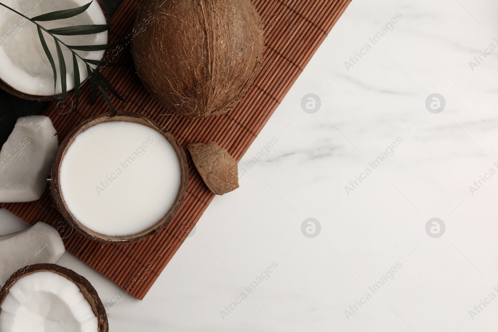 Photo of Delicious vegan milk in coconut and pieces of ripe fruit on white marble table, flat lay. Space for text