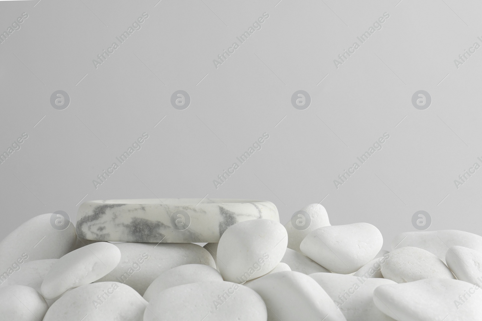 Photo of Presentation for product. Stone podium and white pebbles on light background. Space for text