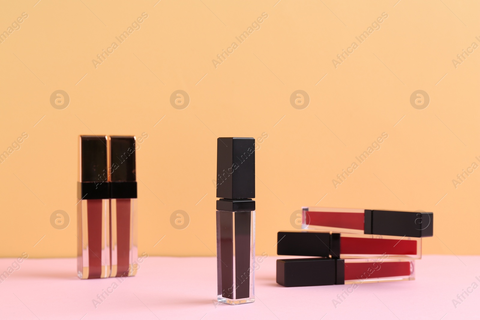 Photo of Many different lip glosses on color background