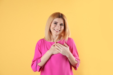 Photo of Portrait of woman holding hands near heart on color background