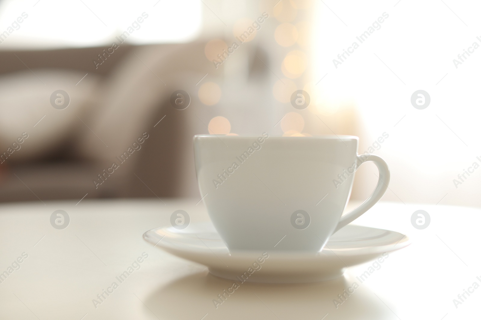 Photo of Cup of hot drink on table against blurred lights. Bokeh effect