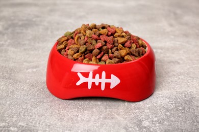 Dry cat food in red pet bowl on grey surface