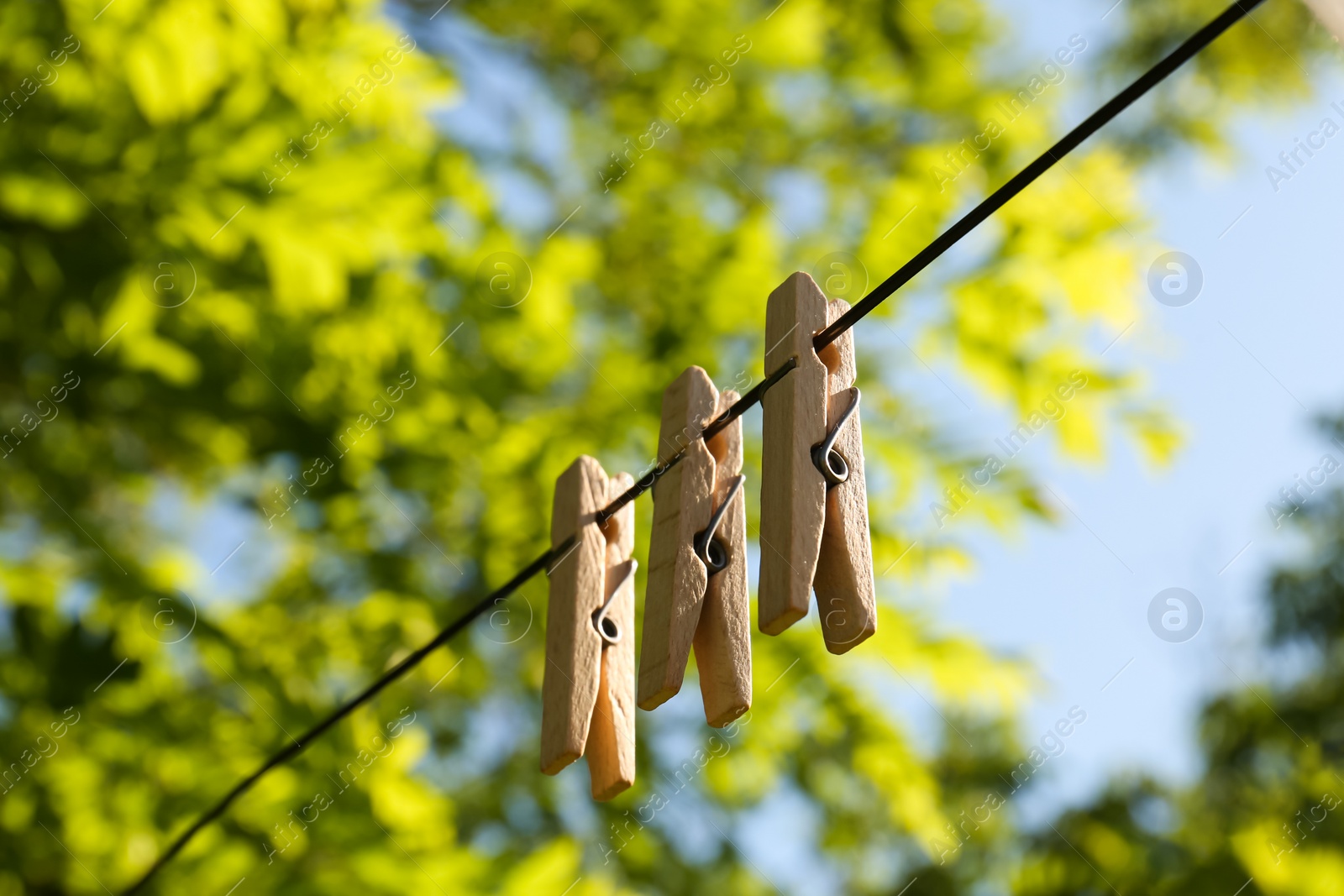 Photo of Wooden clothespins hanging on washing line outdoors