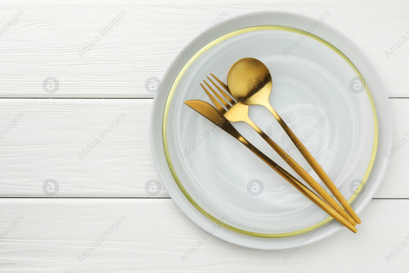 Photo of Stylish setting with cutlery and plate on white wooden table, top view. Space for text