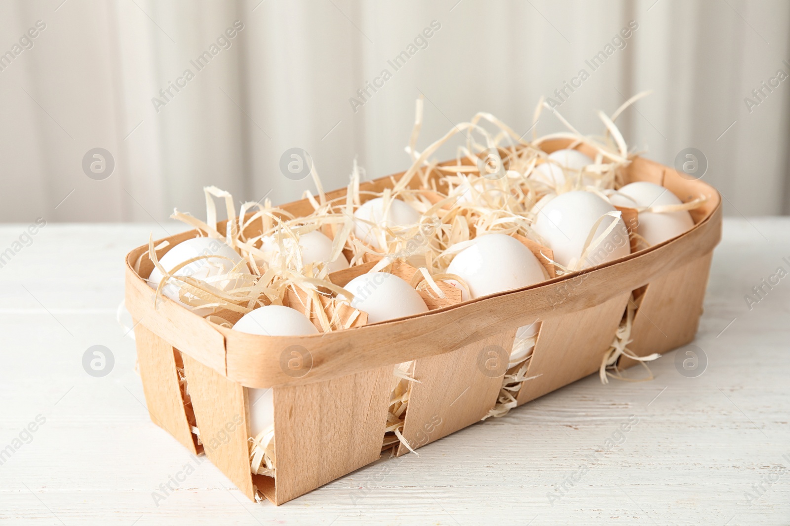 Photo of Basket with raw chicken eggs on wooden table