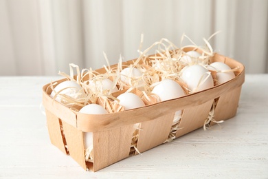 Photo of Basket with raw chicken eggs on wooden table