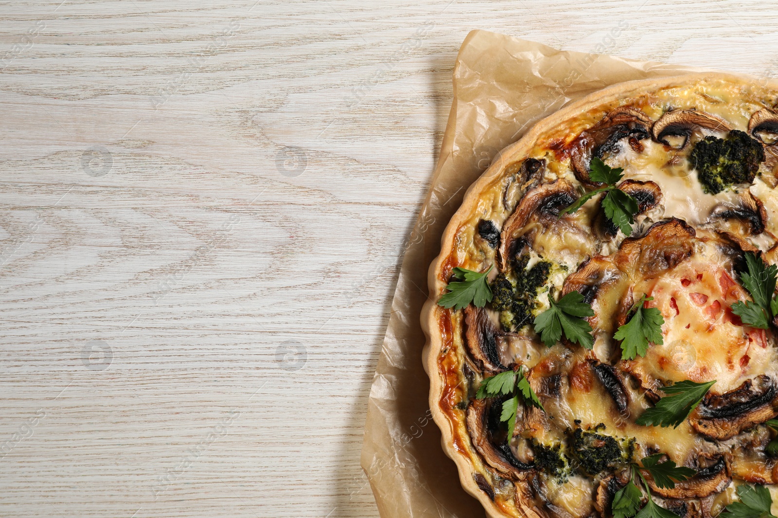 Photo of Delicious quiche with mushrooms and parsley on white wooden table, top view. Space for text