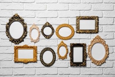 Photo of Blank vintage frames hanging on white brick wall. Mockup for design