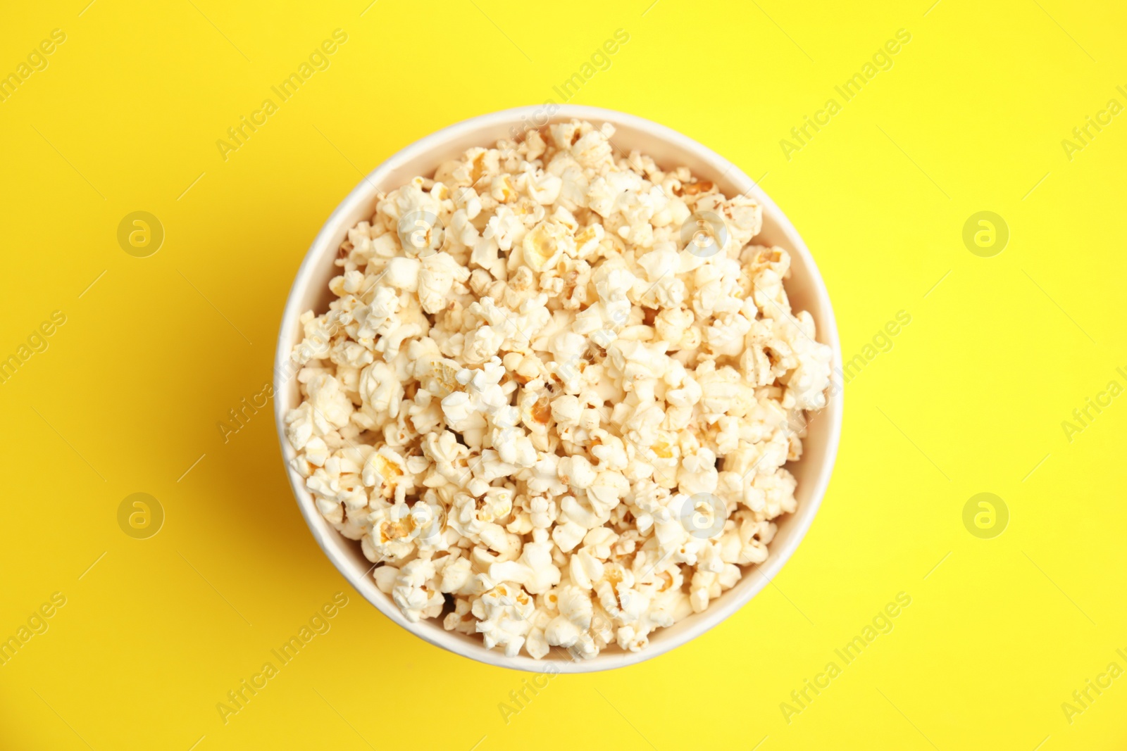 Photo of Tasty pop corn on yellow background, top view