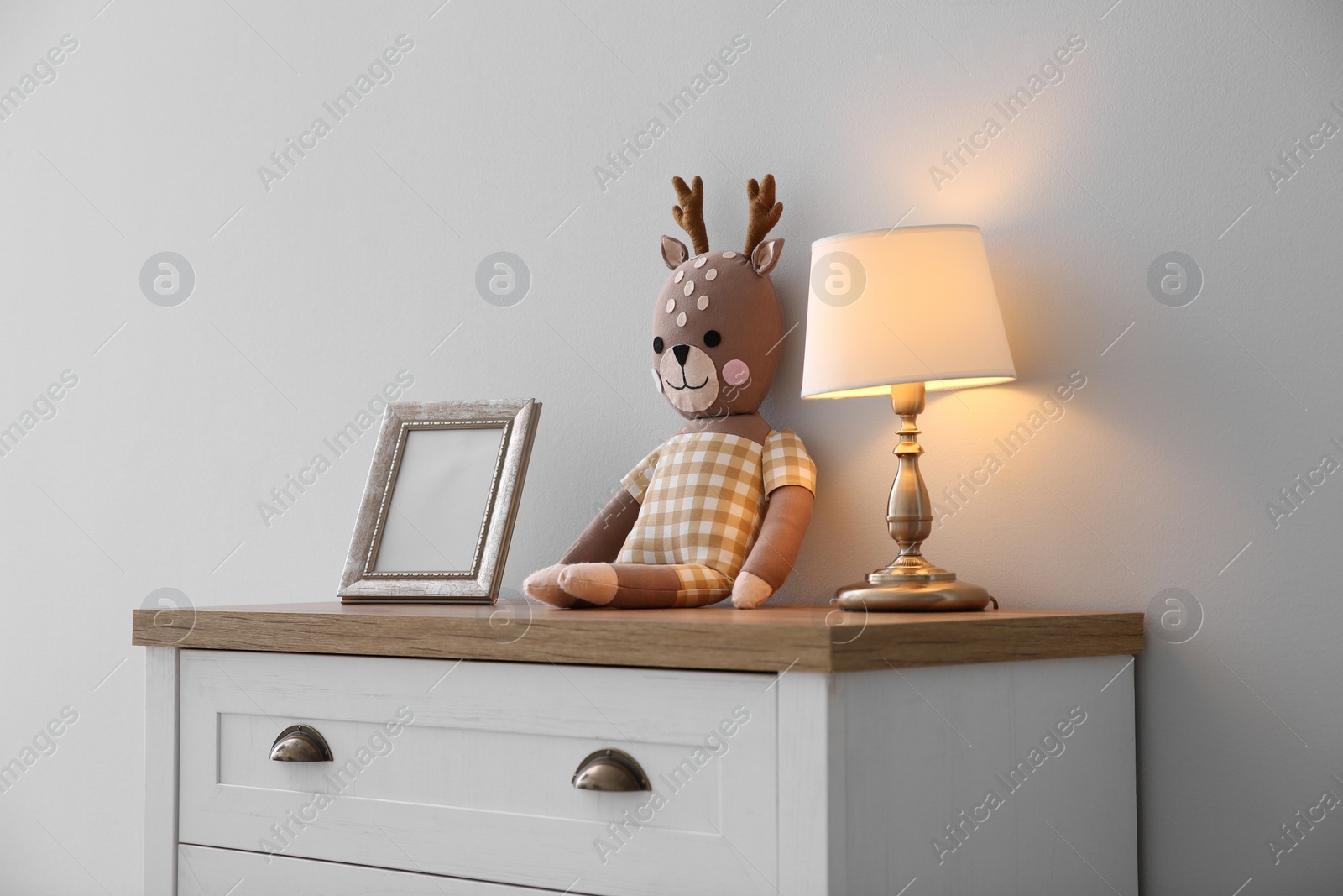 Photo of Modern white chest of drawers near light wall in child room. Interior design