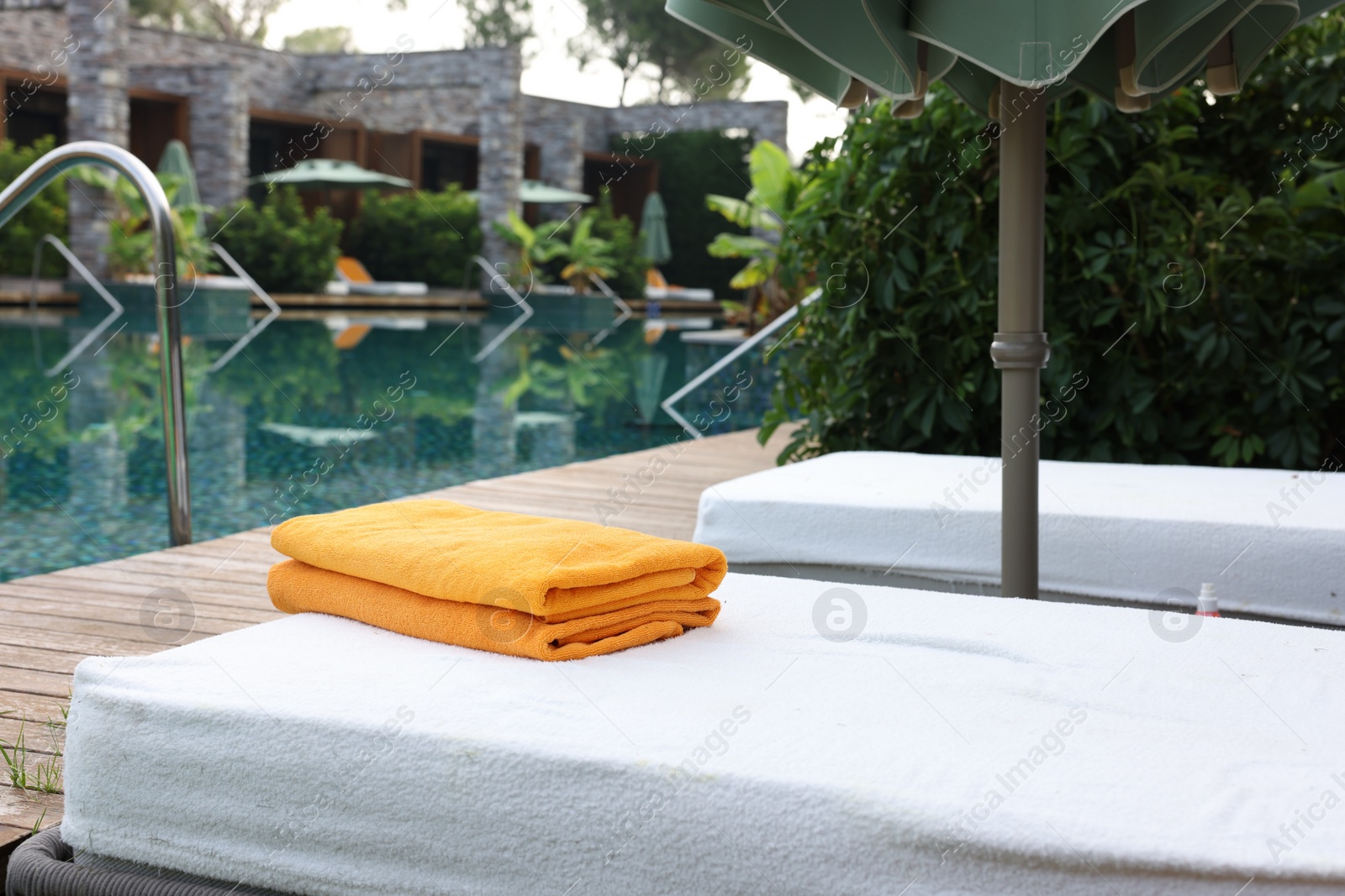 Photo of Sun loungers near outdoor swimming pool at luxury resort