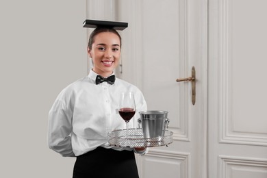 Photo of Woman with tray and book on head practicing good posture indoors, space for text. Professional butler courses
