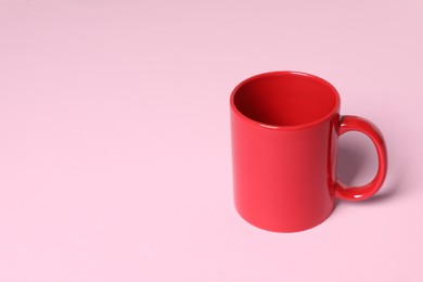 Photo of One red ceramic mug on pink background, space for text